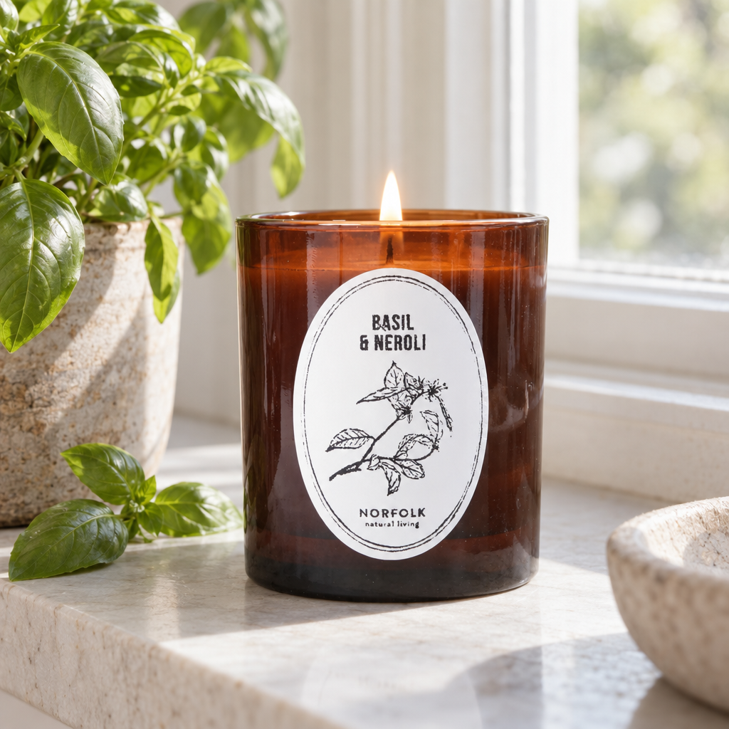 Norfolk Natural Living Basil and Neroli amber glass candle on a windowsill