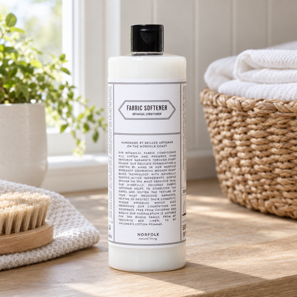 Norfolk Natural Living Fabric Softener beside a basket of folded linen