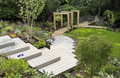 Garden Stewardship: white wooden patio stairs flow down towards a well-maintained lawn