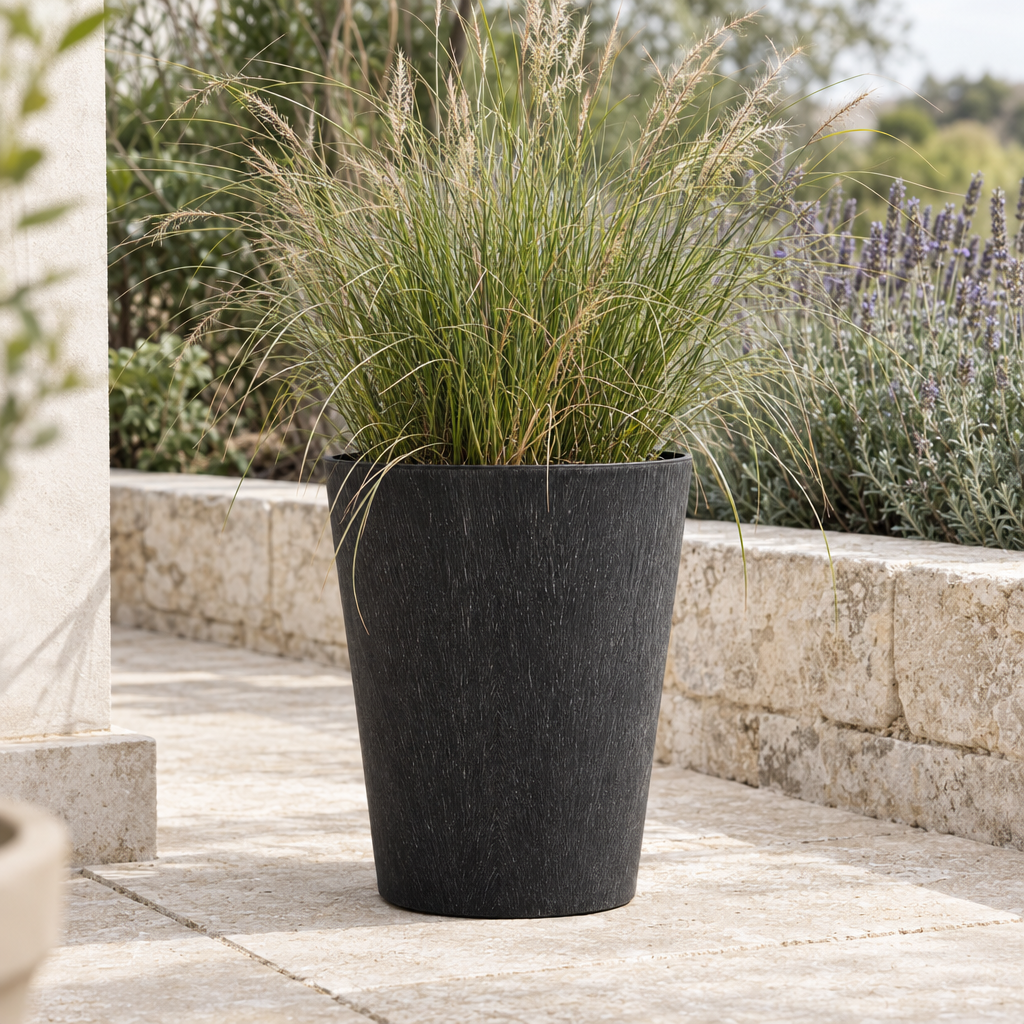 Black Pula lightweight planter with grasses on a limestone terrace
