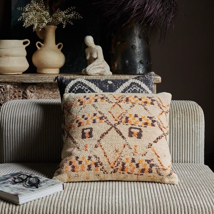The House look cushion on a greay sofa with a book||